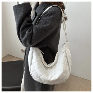 Détail du sac matelassé blanc avec bandoulière réglable sur un manteau sombre