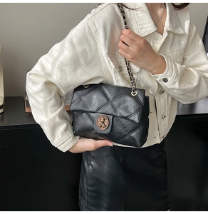 Dettaglio borsa trapuntata nera in pelle con fibbia a testa di leone oro su denim