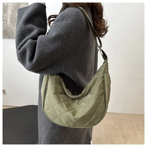 Detail of olive green quilted crescent bag with adjustable strap on wool coat