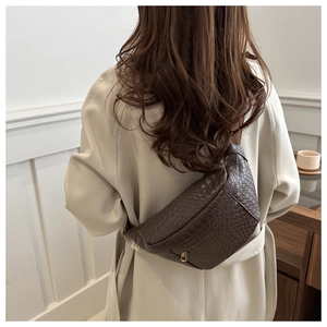 Détail de la texture en cuir tressé marron foncé et de la fermeture éclair du sac banane