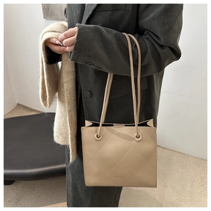 Dettaglio della borsa tote beige trapuntata con trama a rombi e manici sottili