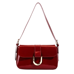 Red patent leather handbag with gold horseshoe buckle and adjustable shoulder strap