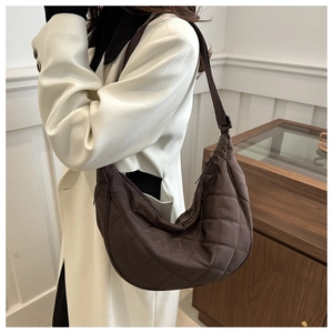 Detail showing deep brown quilted hobo bag texture and adjustable shoulder strap worn by model