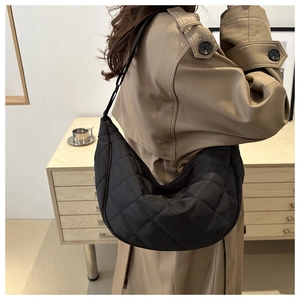 Sac croissant noir matelassé porté sur un mannequin avec un trench-coat kaki décontracté