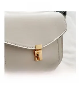 Close-up of white faux leather bag featuring a gold square buckle and fine stitching
