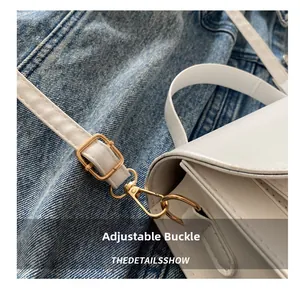 Macro detail of golden metal buckle and white leather strap of the shoulder bag