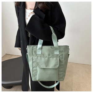 Detail of sage green nylon tote bag featuring thick handles and adjustable shoulder strap