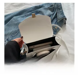 Internal view of a white crossbody bag showing multi-compartments and gold hardware