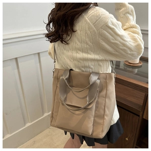 Close-up of khaki nylon tote bag featuring front flap pocket and adjustable shoulder strap