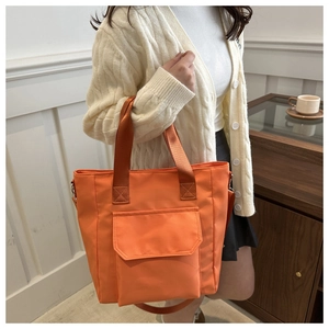 Detail of bright orange nylon tote bag showing flap pocket and reinforced stitching