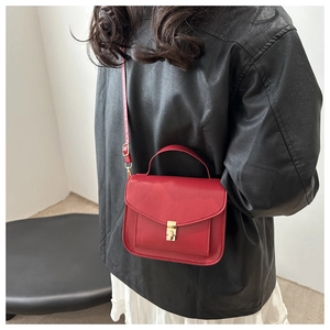 Detail of red leather mini square bag with golden buckle on a black leather jacket