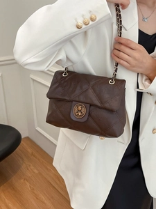 Borsa a tracolla trapuntata marrone con fibbia a orso oro indossata su blazer bianco