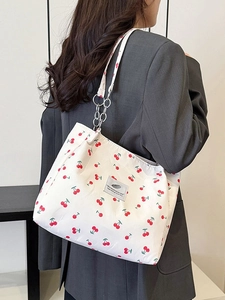 Off-white canvas tote bag with red cherry patterns and elegant metal chain strap