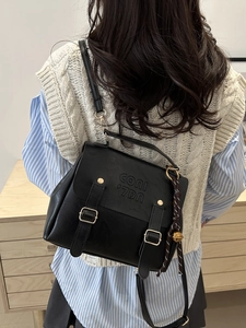 Vintage schwarzer Rucksack mit Metallschnallen und dekorativem Glockenanhänger am Modell
