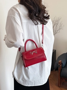 Chic red mini crossbody bag with silver bow accent and polished leather finish
