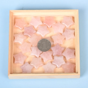 Bulk polished natural rose quartz star pendants displayed on a wooden tray
