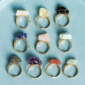 Handmade wire wrapped raw crystal rings in ten colorful natural stones set on a blue tray
