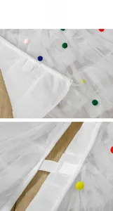 Detail of white mesh skirt with colorful pom-poms and white velcro fastener closure