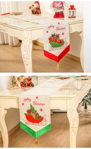 Detail van linnen kersttafellopers met slee-motieven en goudkleurige kwastjes afwerking