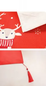 Detailed view of linen Christmas table runner featuring reindeer prints and red tassels