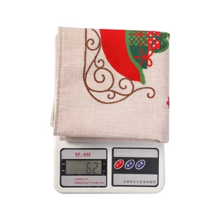 Christmas table mat with red and green festive patterns, weighing 62g on a scale