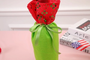Close-up of green felt Christmas wine bottle cover with red sequins and silk ribbon bow