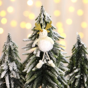 Renne de Noël en peluche blanche avec bois dorés sur un sapin enneigé pour décoration