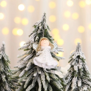 Witte kerstengel met glittervleugels hangend aan een besneeuwde kerstboom
