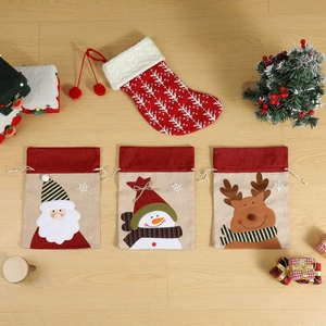 Christmas burlap gift bags set with Santa Claus and snowman motifs on wood background