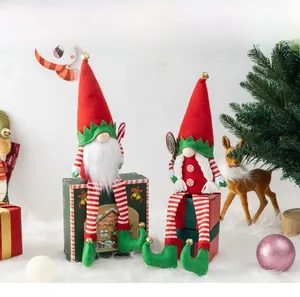 Close-up of plush long-legged Christmas gnomes with bells and candy props in festive scene
