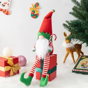 Christmas gnome plush doll with red hat and candy cane sitting on gift box decoration