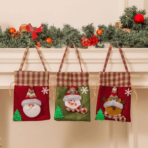 Three Christmas drawstring gift bags featuring Santa, Snowman, and Reindeer on a fireplace