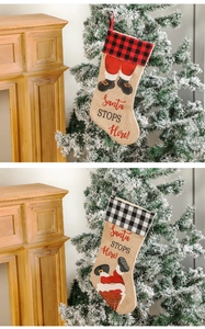 Detail of buffalo plaid Christmas stockings with Santa stops here print on a fireplace