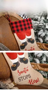 Detail of buffalo plaid Christmas stocking with Santa Stops Here text and red hanger