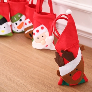 Close-up of red felt Christmas gift bags with cute reindeer and snowman cartoon designs