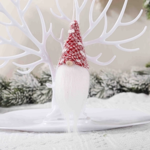 Knitted Christmas gnome ornament with red hat and white beard hanging on antler decor
