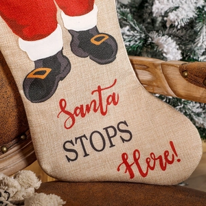 Linen Christmas stocking with Santa Claus legs and Santa STOPS Here print hanging on chair