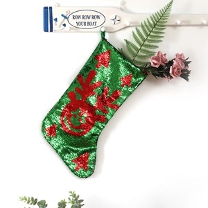 Dettaglio calza di Natale in paillettes rosse e verdi con motivi di renne e alberi
