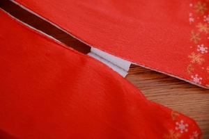 Close-up of white Velcro fastener on red Christmas tree skirt with golden snowflake patterns