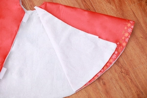 Detail of red Christmas tree skirt with gold snowflakes and white felt backing texture