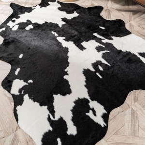 Detailed top view of black and white faux cowhide rug on light herringbone wood floor