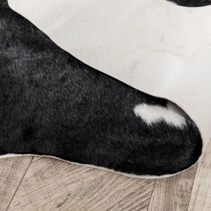 Detailed macro view of black and white cow print faux fur rug with soft texture and non-slip back