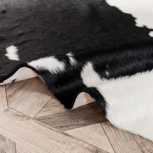 Minimalist black and white cowhide patterned rug with short plush faux fur on wood floor