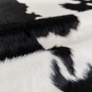 Modern faux cowhide rug with black and white spotted fur pattern for living room decor