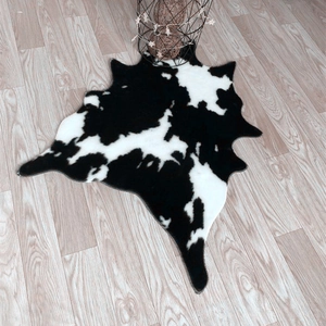 Detailed view of faux cowhide rug with black and white spotted texture on wooden floor