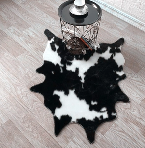 Faux cowhide rug with black and white spots on wood floor in minimalist living room
