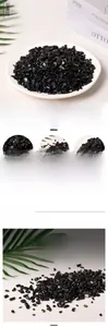 Close-up of polished black obsidian crushed stones with natural glass luster on white surface