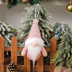 Pink knitted Christmas gnome ornament with white heart patterns and gold star hanging on tree