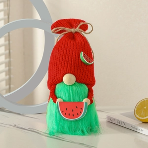 Handmade summer watermelon gnome with red knitted hat and green plush body on marble desk