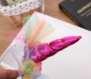 Detail of unicorn headband with pink horn, colorful tulle, and flowers on a white band